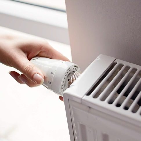 Woman Adjusting the Controls on a Heater — Heating & Cooling in Central West NSW